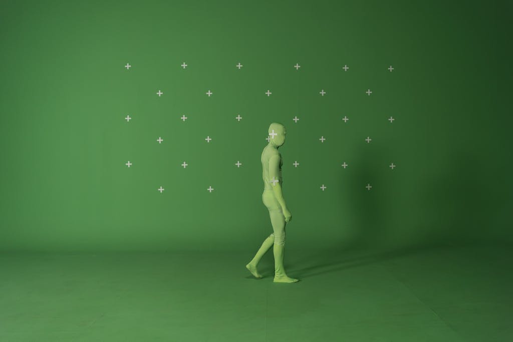 Person walking in a chroma key suit in a studio with green screen for video editing.
